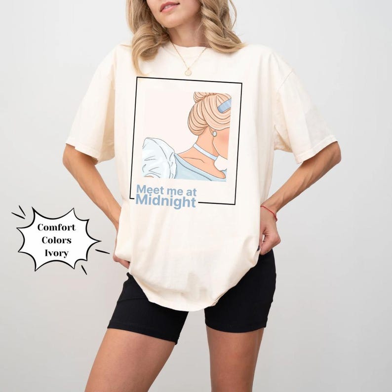 May include: A white t-shirt with a graphic of a woman with blonde hair and a blue dress. The text "Meet me at Midnight" is printed below the graphic.