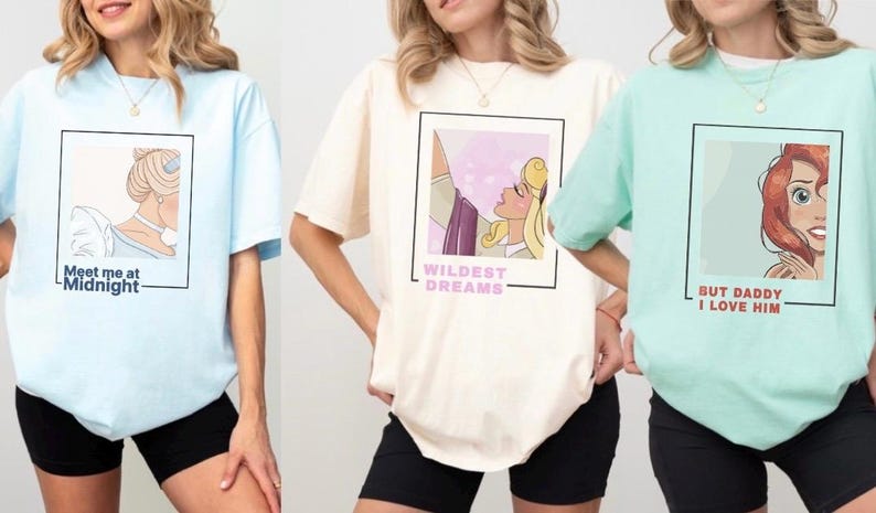 May include: Three light-colored t-shirts with different Disney princess graphics and text. The first shirt is light blue with a graphic of Cinderella and the text "Meet me at Midnight". The second shirt is cream with a graphic of Aurora from Sleeping Beauty and the text "Wildest Dreams". The third shirt is light green with a graphic of Ariel from The Little Mermaid and the text "But Daddy I Love Him".