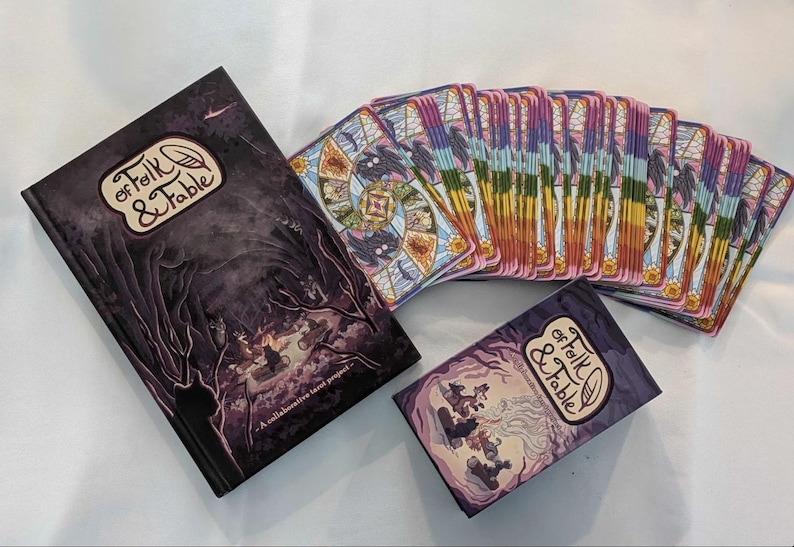May include: A set of playing cards with a purple and gold design. The cards are in a stack and have a title that reads "Of Folk & Fable". A book with the same title is also pictured.