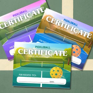 May include: Three colourful pickleball certificates of achievement. Each certificate features a pickleball court illustration, a pickleball, and the text "PICKLEBALL CERTIFICATE OF ACHIEVEMENT". The certificates are in shades of purple, blue, and green.