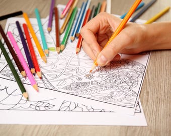Può includere: Una persona sta colorando un disegno dettagliato in bianco e nero con una varietà di matite colorate. Il disegno presenta intricati motivi floreali e vortici.