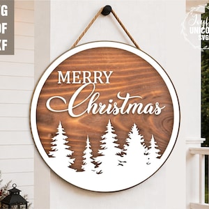 May include: A round wooden sign with a white border and a rope hanger. The sign features the words "MERRY Christmas" in white script above a white silhouette of pine trees. The background is a wood grain pattern.