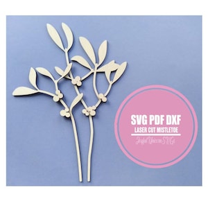 Puede incluir: Un diseño de muérdago de madera cortado con láser con hojas y bayas. El diseño es de color claro y está sobre un fondo azul. El texto en un círculo rosa dice "SVG PDF DXF LASER CUT MISTLETOE".