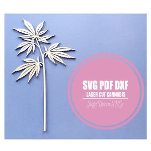 Könnte beinhalten: Ein lasergeschnittenes Cannabisblatt-Design aus hellem Holz vor blauem Hintergrund. Der Text "SVG PDF DXF LASER CUT CANNABIS Joyful Unicorn SVGs" ist in einem rosa Kreis enthalten.