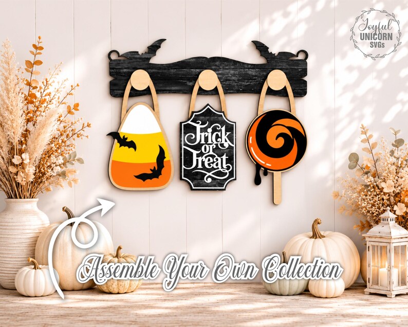 Puede incluir: Un estante de pared de madera negra con siluetas de murci&eacute;lagos que presenta tres decoraciones colgantes: una forma de caramelo de ma&iacute;z con murci&eacute;lagos, un letrero negro con texto blanco Trick or Treat y una forma de piruleta naranja y negra.