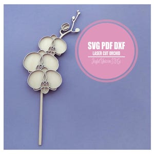 Könnte beinhalten: Ein lasergeschnittenes Orchideen-Design aus hellem Holz mit detaillierten Blütenblättern und Stiel. Das Design enthält den Text "SVG PDF DXF LASER CUT ORCHID" in einem rosa Kreis, darunter der Text "Joyful Unicorn SVGs".