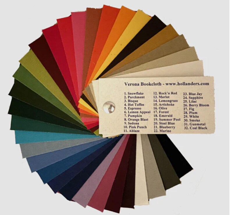 May include: A color chart of 32 fabric swatches, arranged in a fan shape. The swatches are labeled with numbers and names, such as "Snowflake", "Parchment", "Bisque", "Hot Toffee", "Espresso", "Lemon Appeal", "Pumpkin", "Orange Blast", "Sedona", "Pink Punch", "Ablaze", "Rock'n Red", "Merlot", "Lemongrass", "Artichoke", "Olive", "Forest", "Emerald", "Summer Pool", "Steel Blue", "Blueberry", "Marine", "Blue Jay", "Sapphire", "Lilac", "Berry Bloom", "Fig", "Plum", "White", "Smoke", "Gunmetal", and "Coal Black". Verona Bookcloth - www.hollanders.com is printed on the chart.