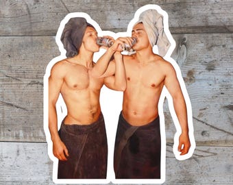 Puede incluir: Una pegatina con dos figuras sin camisa, cada una con una toalla en la cabeza y envuelta en una toalla. Están bebiendo de latas plateadas. El fondo es un patrón de vetas de madera.