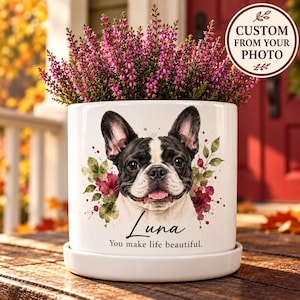 May include: A white ceramic planter with a saucer featuring a watercolor illustration of a black and white French Bulldog, the name Luna, and the text You make life beautiful, topped with a vibrant purple heather plant.
