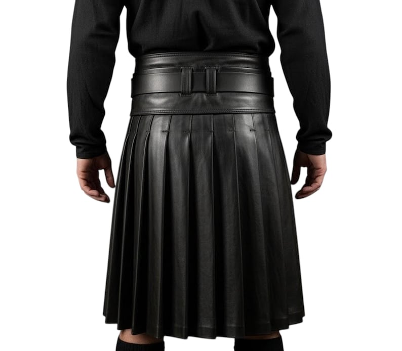 K&ouml;nnte beinhalten: Ein schwarzer Lederkilt mit tiefen Falten und einem breiten G&uuml;rtel mit Schnalle. Der Kilt wird mit einem schwarzen Langarmshirt getragen. Das Bild zeigt die R&uuml;ckansicht des Kilts.