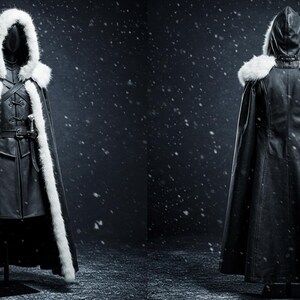 May include: A black hooded cloak with a white fur trim. The cloak is lined with a black fabric and has a long, flowing design. The cloak is shown on a mannequin against a dark background with a snowy effect.