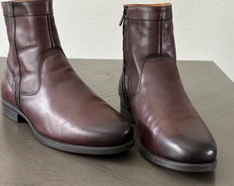 May include: A pair of burgundy leather ankle boots. The boots have a rounded toe, a side zipper, and a low heel. The leather has a polished finish and a subtle color variation.