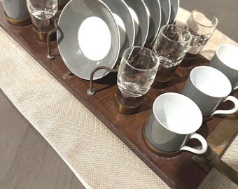 May include: A wooden serving tray with a set of gray and white espresso cups and saucers, and clear glass shot glasses. The tray has a brass handle.