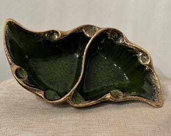 May include: A green ceramic divided dish with gold accents. The dish has two sections and a unique, organic shape.