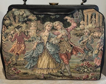 May include: A black vintage handbag with a tapestry design featuring a couple dancing in a garden setting. The tapestry is in shades of green, brown, pink, and blue.