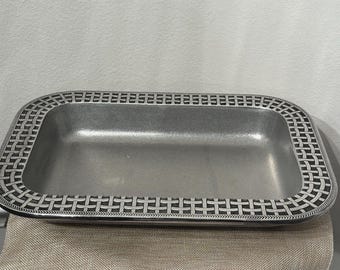 May include: A rectangular metal tray with a decorative border. The tray has a silver finish and a woven pattern around the edges. The tray is empty and sits on a tan surface.