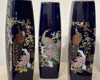May include: Three blue ceramic vases with gold trim and a peacock design. The vases are decorated with gold and pink flowers and leaves.