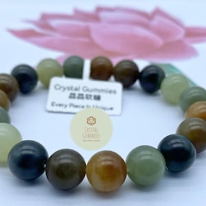Puede incluir: Una pulsera de cuentas con una variedad de piedras preciosas de tonos tierra, incluyendo tonos de verde, marrón y negro. La pulsera tiene una mezcla de cuentas mate y pulidas. Una pequeña etiqueta dice "Crystal Gummies".