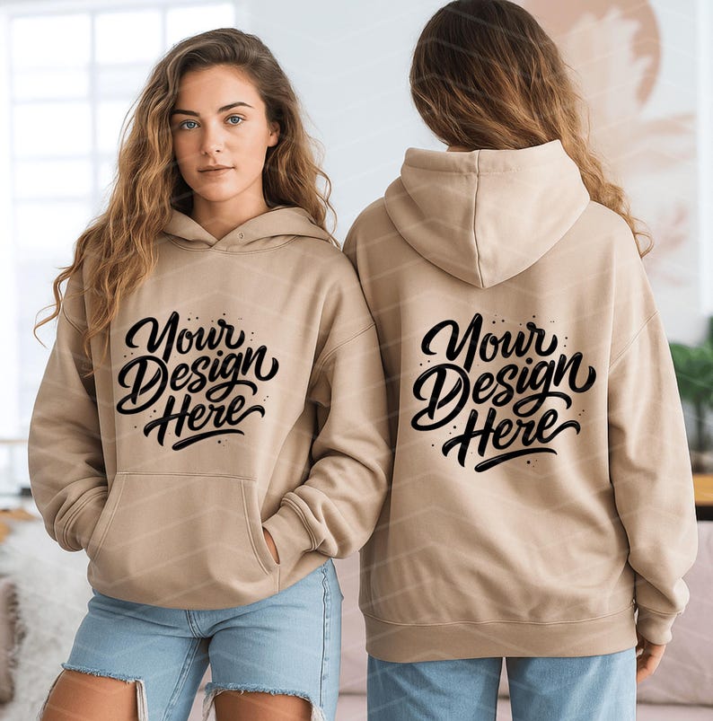 May include: A tan hoodie with a front pocket and a hood. The front of the hoodie features the text "Your Design Here" in a black script font. The back of the hoodie also displays the same text. The hoodie is worn by a person.