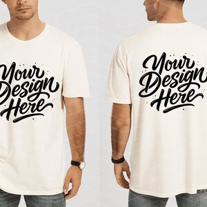 May include: Cream-colored t-shirt with the text "Your Design Here" in a black, stylized script on the front and back. The shirt is short-sleeved and has a relaxed fit. The model is wearing blue jeans and a watch.
