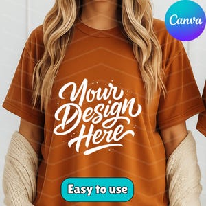May include: A burnt orange t-shirt with the words "Your Design Here" in white script. The shirt also has the words "Easy to use" in a blue rectangle. The Canva logo is in the upper right corner.