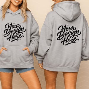 May include: Light gray hoodie with a front pocket and a hood. The front and back of the hoodie feature the text "Your Design Here" in a black script font. The model is wearing denim shorts.