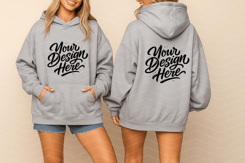 May include: Light gray hoodie with a front pocket and a hood. The front and back of the hoodie feature the text "Your Design Here" in a black script font. The model is wearing denim shorts.