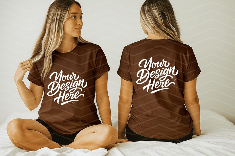 May include: Two brown t-shirts with the text "Your Design Here" in white script. The shirts are on a person sitting on a bed. The person is wearing black shorts. The background is a light color with a chevron pattern.