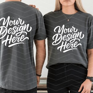 May include: Two charcoal gray t-shirts with the text "Your Design Here" in white script. The shirts are worn by two people. The background has a chevron pattern.