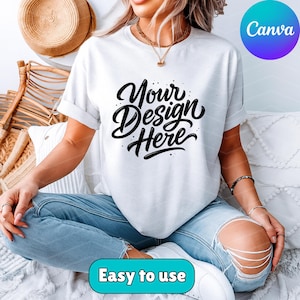 May include: White t-shirt with the text "Your Design Here" in a black, cursive font. The shirt is being worn with blue jeans. The image also includes the text "Easy to use" and the Canva logo.