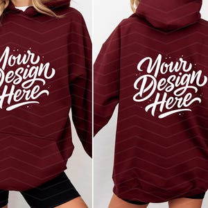 May include: Burgundy hoodie with the text "Your Design Here" in white script on the front and back. The hoodie has a front pocket and a hood. The background has a subtle chevron pattern.