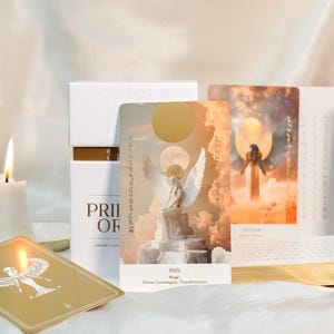 May include: A white box set of tarot cards with gold accents, featuring cards with angel illustrations. One card displays the word "ISIS" with "Magic, Divine Sovereignty, Transformation" below. The set is titled "PRIOR OF DIVINE LIGHT".