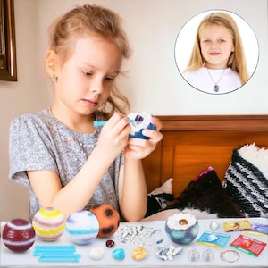 May include: A child digs for gemstones inside a colorful, cracked egg. The kit includes several colorful eggs, tools, and a variety of gemstones. The child is wearing a necklace with a gemstone pendant.