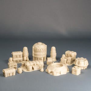 May include: A set of beige miniature structures, including cylindrical tanks, rectangular buildings, and dome-shaped components. These pieces are designed for tabletop gaming, creating a futuristic or industrial setting.