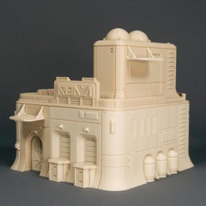 Könnte beinhalten: Ein beigefarbenes, detailliertes, mehrstöckiges 3D-gedrucktes Gebäudemodell mit einem Flachdach und einer abgerundeten Basis. Das Gebäude verfügt über eine Vielzahl von Fenstern, Türen und anderen architektonischen Merkmalen.