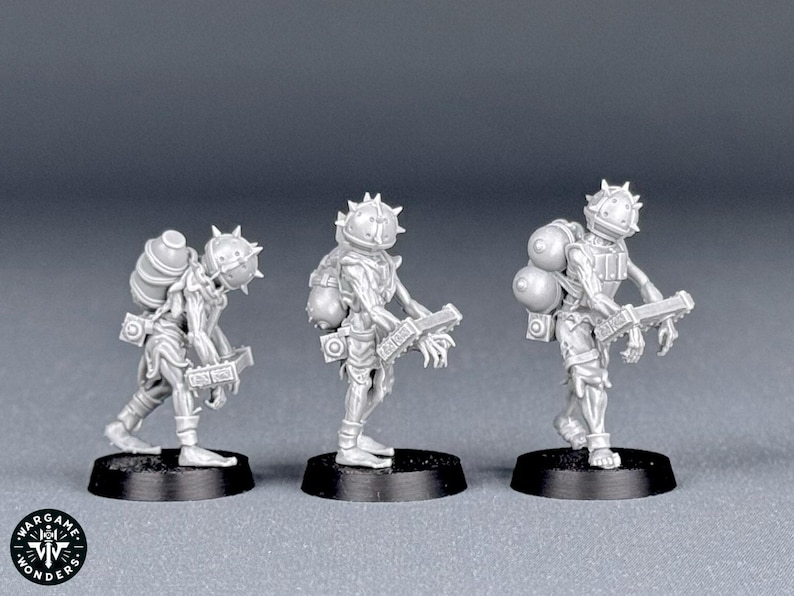 May include: Three miniature figurines of a futuristic soldier, each standing on a black base. The soldiers wear helmets with spikes, backpacks, and carry a weapon. The figures are a light gray color.