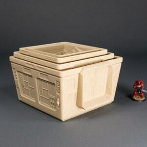 May include: A beige, multi-level, modular building with windows and a door. The building is made of plastic and is designed for use in tabletop games.