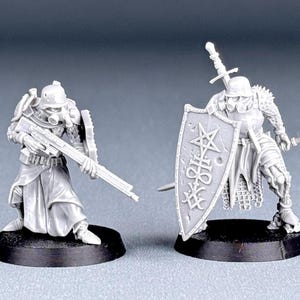 May include: Two unpainted miniature figures, one holding a rifle and the other holding a sword and shield. The shield has a pentagram and the word "VOID" inscribed on it.