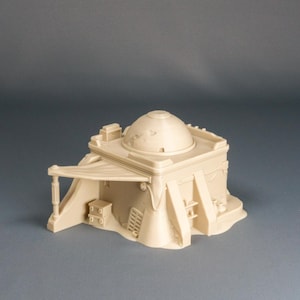 Könnte beinhalten: Ein beigefarbenes Miniaturgebäude mit einem Kuppeldach, einer Markise und verschiedenen architektonischen Details. Das Modell umfasst eine kleine Leiter, einen Schrank und dekorative Elemente, geeignet für Tabletop-Spiele oder Ausstellungen.