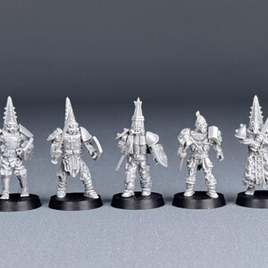 May include: Five grey plastic miniature figures of warriors wearing helmets and armor, standing on black circular bases.
