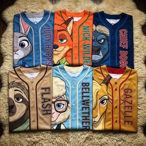 May include: Baseball jerseys featuring characters from Zootopia. The jerseys are in various colors, including blue, orange, and tan, with character faces and names like "Judy Hopps" and "Nick Wilde" printed on them. The jerseys are button-down.