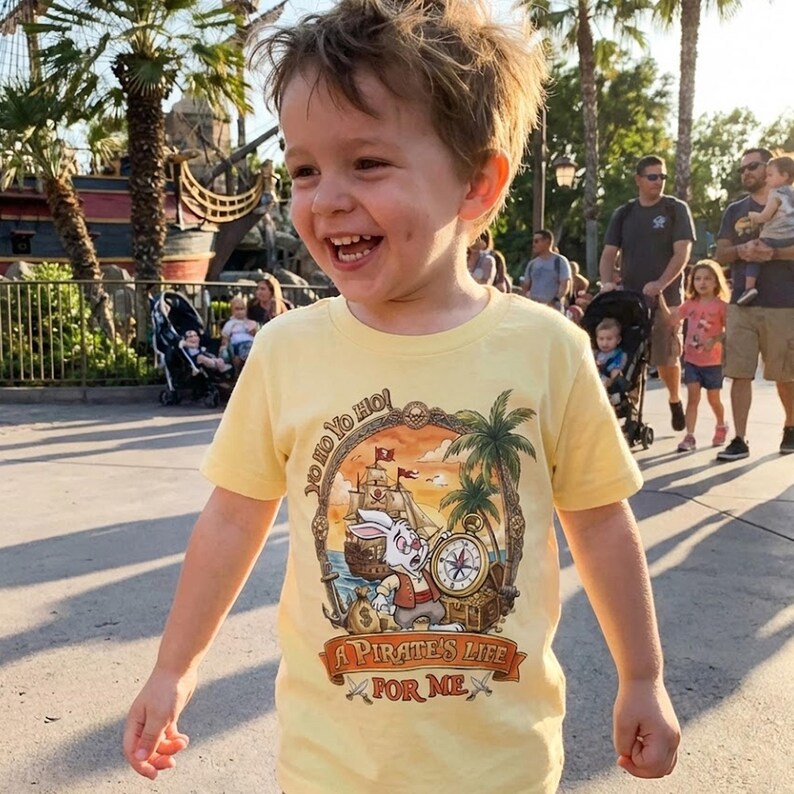 Pu&ograve; includere: Una maglietta gialla con una grafica a tema pirata. La grafica presenta un coniglio dei cartoni animati, una nave pirata, una bussola e la scritta "A Pirate's Life For Me". La maglietta ha anche la frase "Yo Ho Yo Ho".