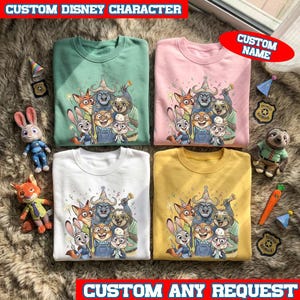 Może przedstawiać: Cztery bluzy z okrągłym dekoltem w kolorze zielonym, r&oacute;żowym, białym i ż&oacute;łtym, każda z kolorową grafiką postaci Disneya. Obraz zawiera pluszowe zabawki i naszywki. Tekst na obrazie brzmi "CUSTOM DISNEY CHARACTER", "CUSTOM NAME" i "CUSTOM ANY REQUEST".