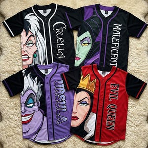 May include: Baseball jerseys featuring villainous characters Cruella, Maleficent, Ursula, and the Evil Queen. Each jersey has a character's face on the front and the character's name printed vertically. The jerseys are black, red, and purple with contrasting sleeves and trim.