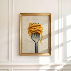 May include: A framed painting depicts a fork with a large serving of spaghetti. The fork is dark gray, and the pasta is a vibrant yellow-orange. The painting has a gold frame and is set against a textured, off-white background.