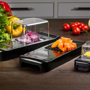 May include: Three black plastic food choppers with clear plastic containers. The choppers have different sized grids for slicing, dicing, and grating. The containers are filled with chopped red onion, diced carrots, and grated cheese.