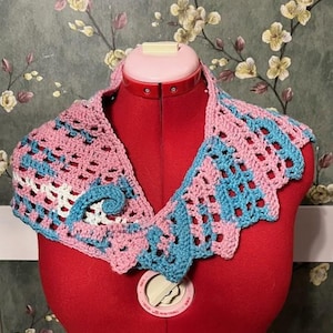 May include: A crocheted collar in pink, blue, and white. The collar is made of a delicate, lacy pattern and is perfect for adding a touch of vintage style to any outfit.