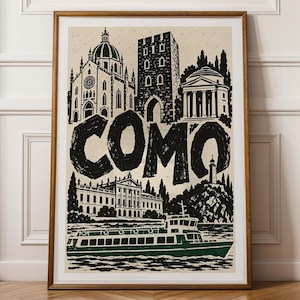 May include: A framed art print featuring a black and white illustration of the city of Como, Italy. The design includes architectural landmarks, a lighthouse, and a green passenger boat on the water, with the word COMO in large bold letters.