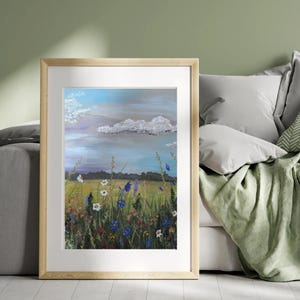 May include: A framed painting of a field of wildflowers with a blue sky and white clouds in the background. The flowers are a variety of colors, including blue, white, and yellow.