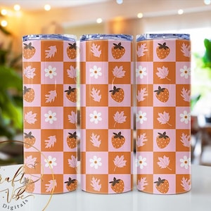 Puede incluir: Tres vasos de acero inoxidable con un patrón de cuadros rosa y naranja con fresas y flores blancas.